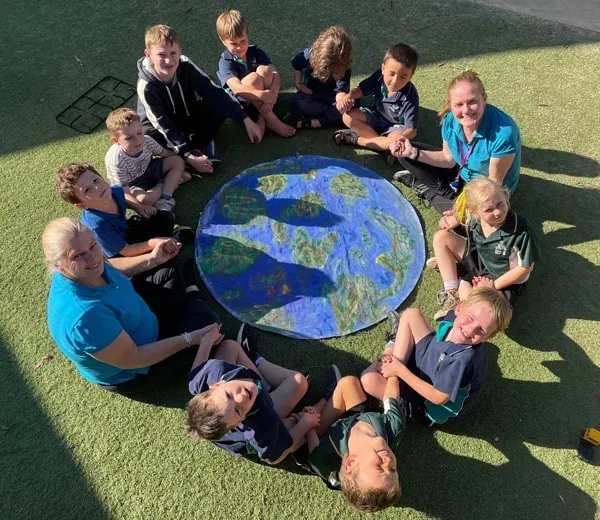 Children and educators sitting in a circle on the grass